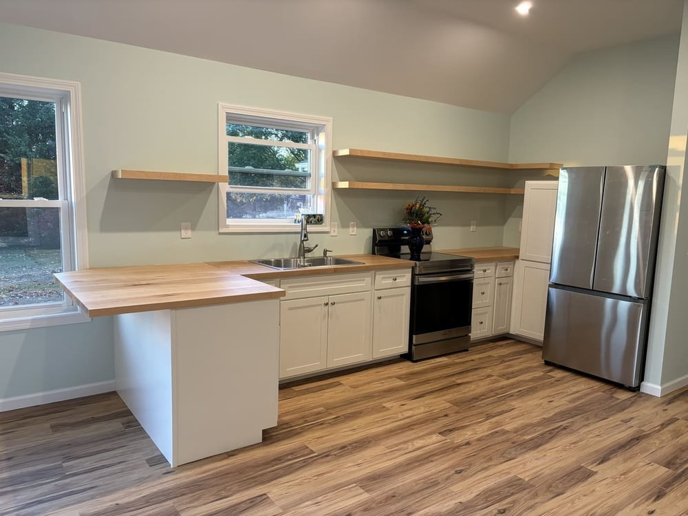 Kitchen with floating wood shelves, white cabinetry, and vinyl flooring in a Central Connecticut home by Riverbend Renovations