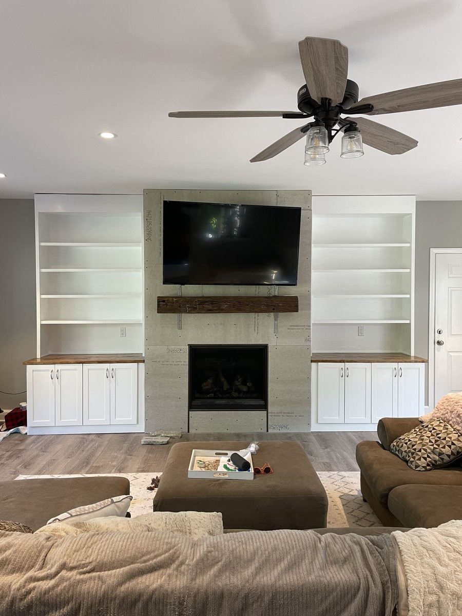 Living room with built-in shelves, fireplace, and mounted TV in Central Connecticut home by Riverbend Renovations