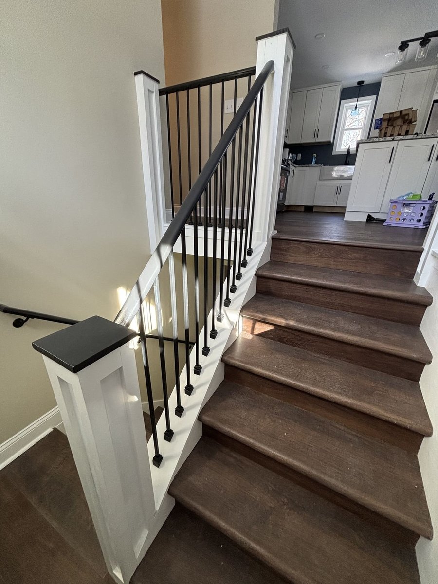 Stained wood stairs with white railing and black balusters in a Central Connecticut home by Riverbend Renovations