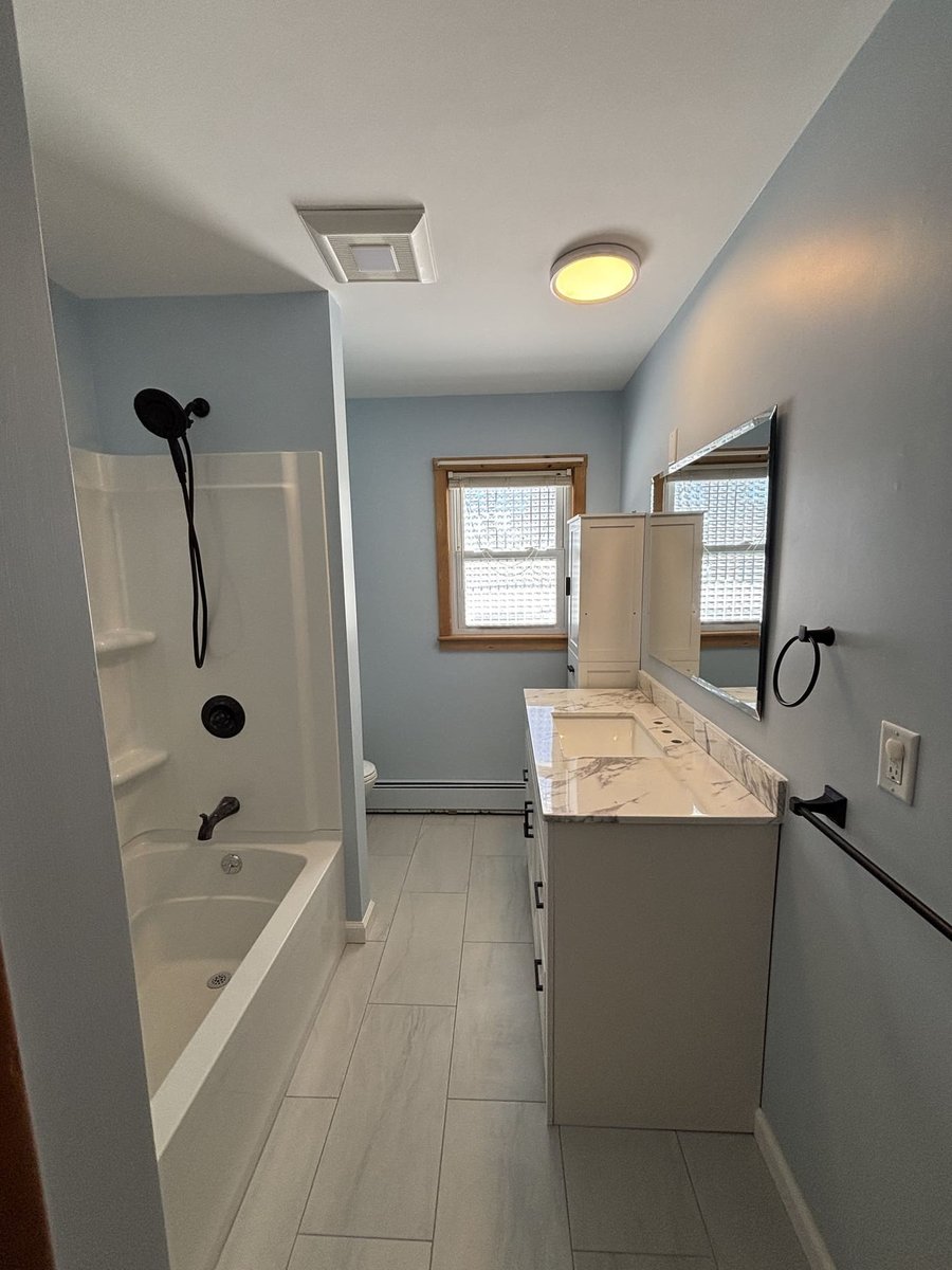 Updated bathroom with tub shower, marble vanity, and tile floor in a Central Connecticut home by Riverbend Renovations