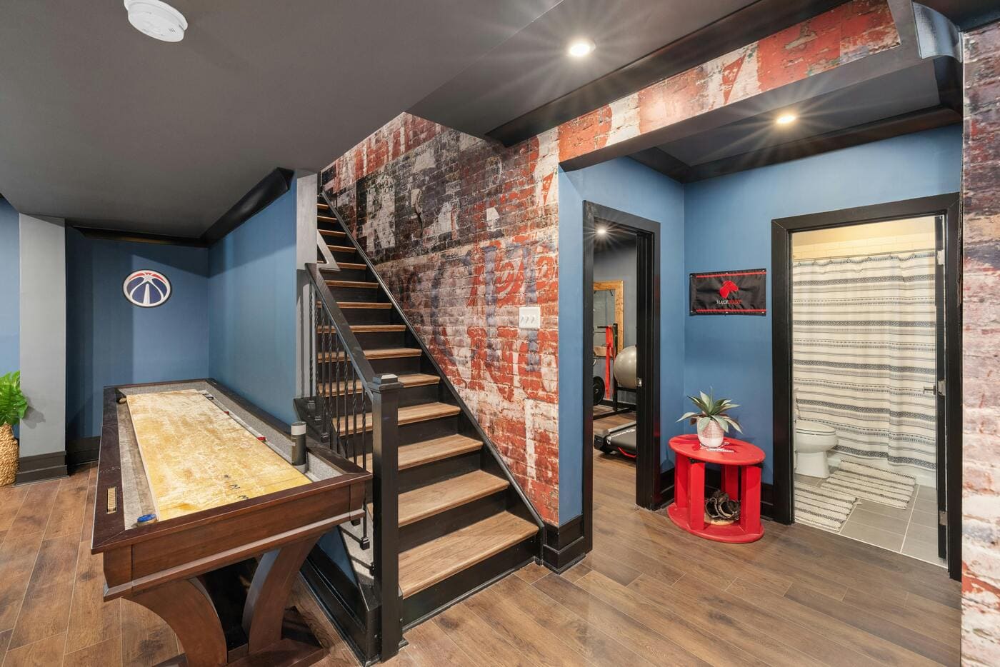 Basement rec room with shuffleboard, brick accent wall, and stairs in South Windsor, CT