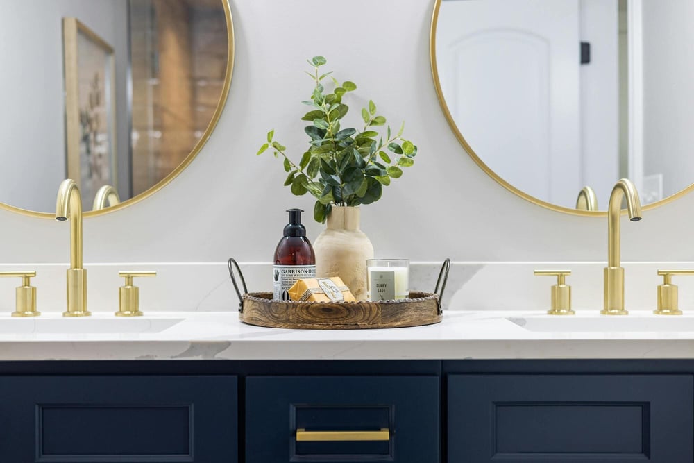 Remodeled bathroom vanity with double sinks, gold fixtures, and round mirrors in Middletown, CT
