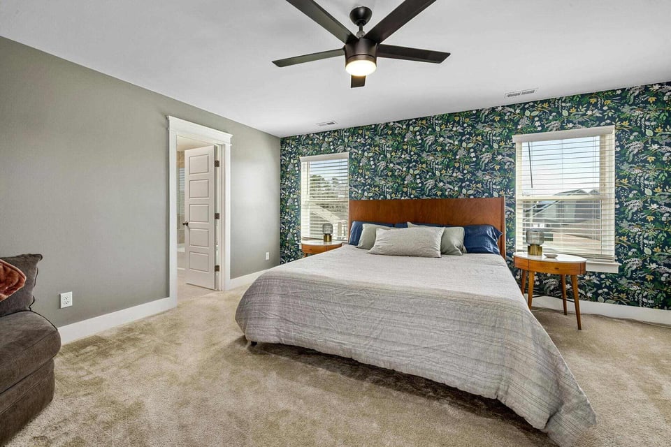 Stock image of bedroom with patterned accent wall, wood bed, and ceiling fan in Central Connecticut