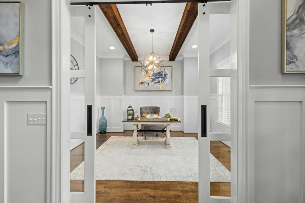 home office with sliding doors, wood beams, desk, and neutral decor in Tolland, CT