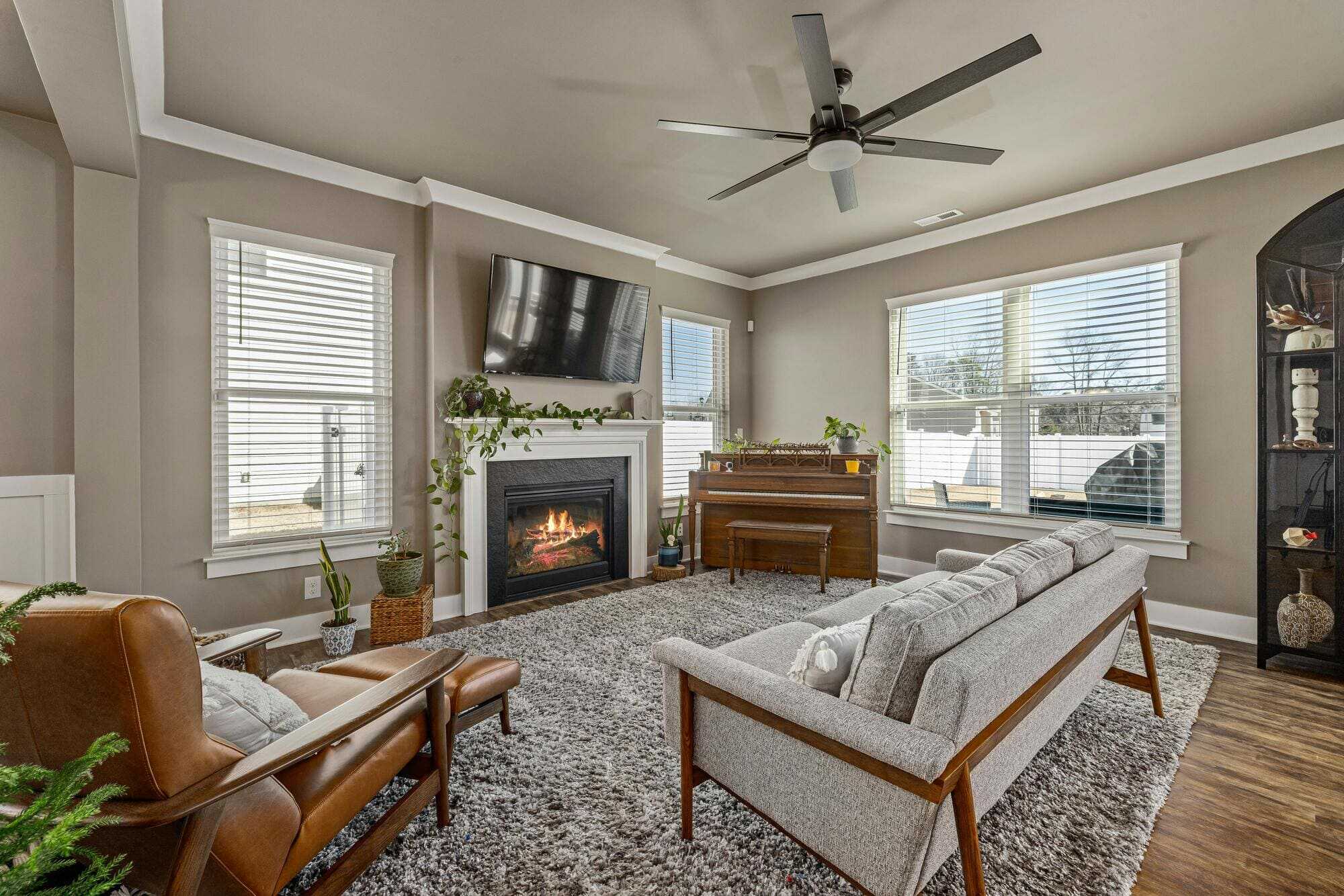 Remodeled living room with fireplace, TV, and piano, surrounded by windows in Glastonbury, CT 