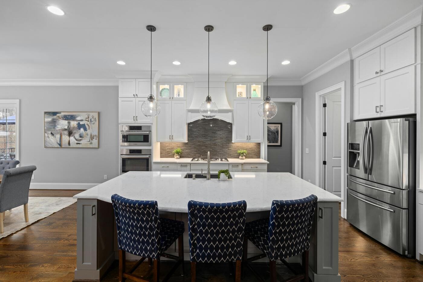 Modern kitchen with large island, pendant lights, white cabinets, and stainless appliances in Glastonbury, CT