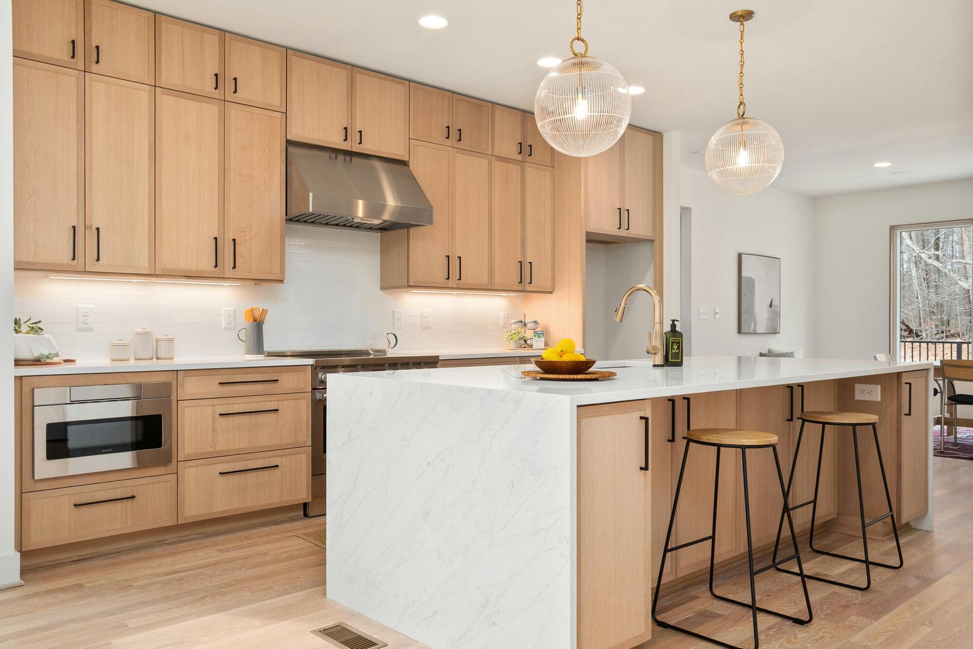 Stock image of modern kitchen with light wood cabinets, large island, and pendant lights in South Windsor, CT
