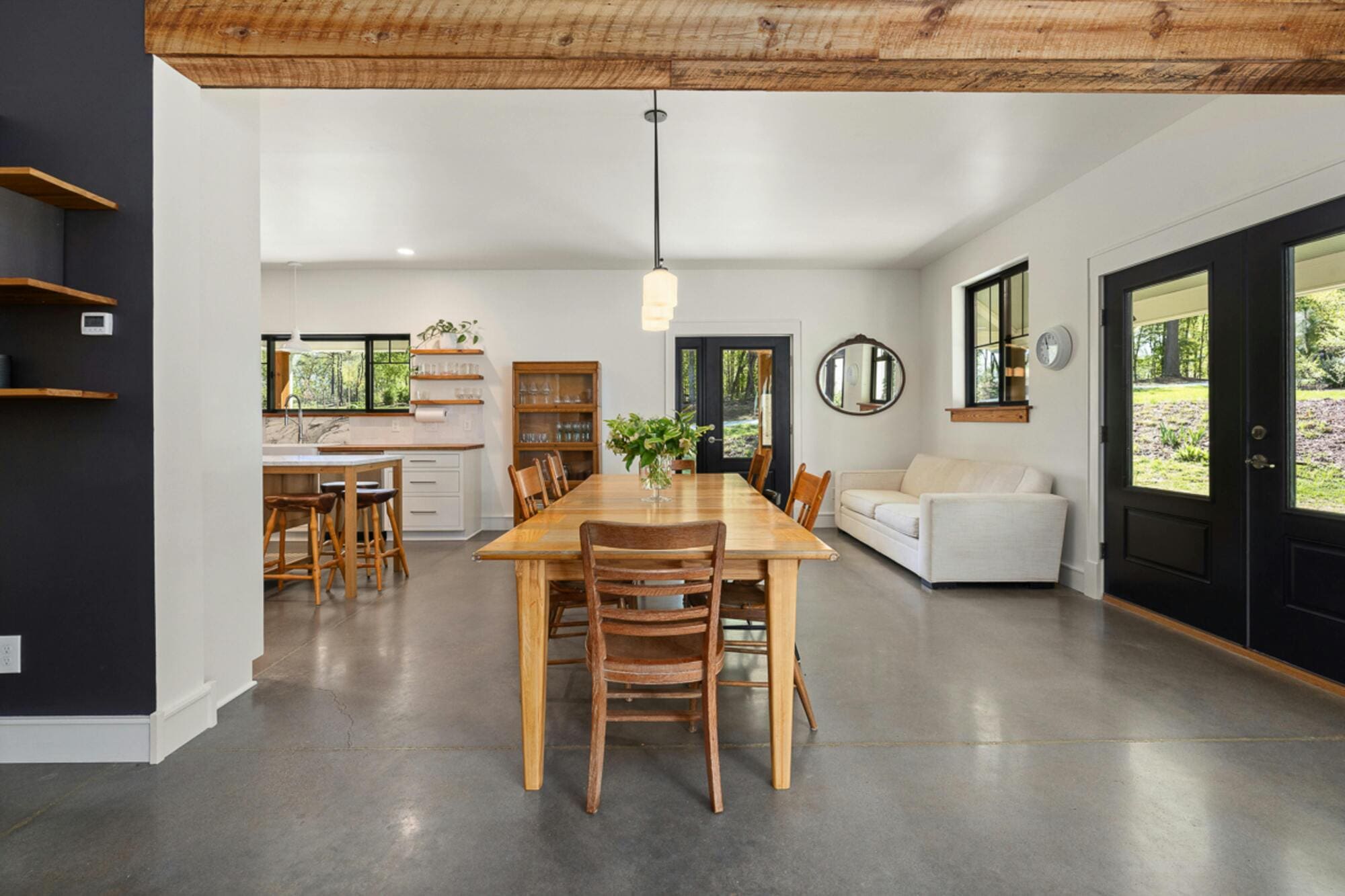Stock image of open dining and kitchen area with wood table, chairs, and natural light in South Windsor, CT