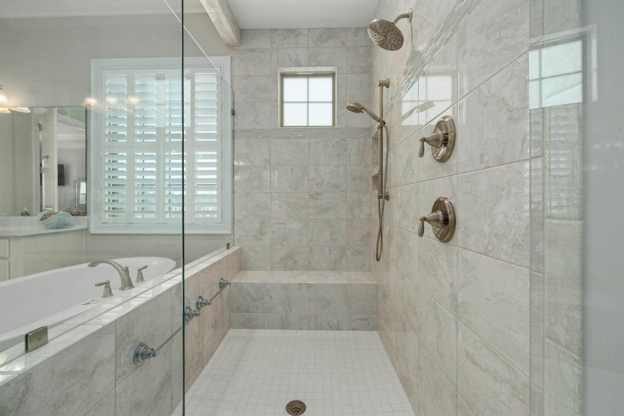 Tiled walk-in shower with glass enclosure, dual shower heads, and bench in Glastonbury, CT